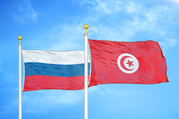 Russia and Tunisia two flags on flagpoles and blue cloudy sky
