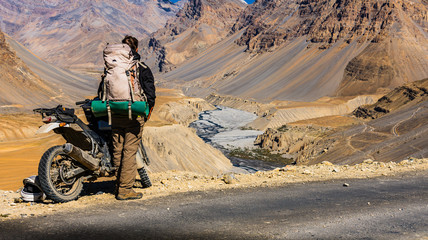 solo traveller with a motorbike looking into an epic mountain scenery