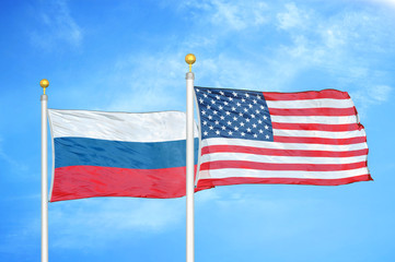 Obraz premium Russia and United States two flags on flagpoles and blue cloudy sky