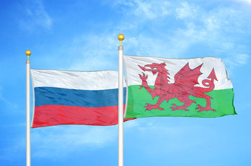 Russia and Wales two flags on flagpoles and blue cloudy sky