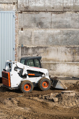 Fototapeta na wymiar White skid steer loader at a construction site working with a soil. Industrial machinery. Industry.