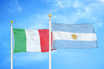 Italy and Argentina  two flags on flagpoles and blue cloudy sky