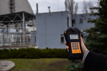 Geiger counter orange with a hand and buildings in background