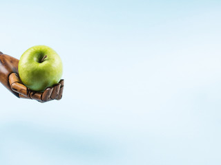 Fresh green apple in palm of wooden hand on blue background