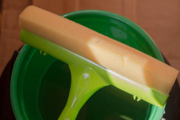 Tools for washing Windows in the apartment. A scraper with a sponge close-up on a bucket of water...