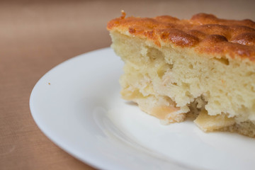 Sweet homemade cakes with apples. A slice of sponge Apple pie with a ruddy crust on a white plate close-up on a beige textile linen background.
