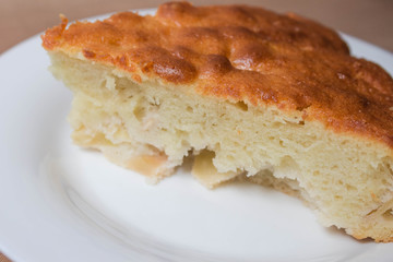 Sweet homemade cakes with apples. A slice of sponge Apple pie with a ruddy crust on a white plate close-up on a beige textile linen background.