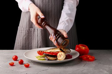 the chef is cooking grilled vegetables. pepper. female hands of the chef. on a black background