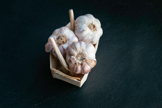 Garlic. Fresh garlic bulbs in vintage bowl over dark stone background. Top view on dark stone table.