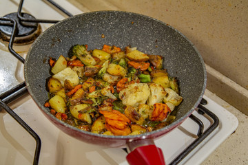 Vegetables are fried in a pan with seed oil on a gas stove