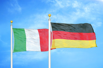 Italy and Germany two flags on flagpoles and blue cloudy sky