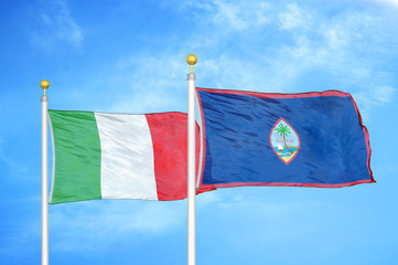 Italy and Guam two flags on flagpoles and blue cloudy sky