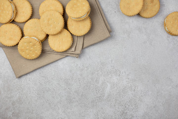 Sandwich cookies on a beige towel. On a light gray concrete background. Double cookies with white cream filling. Top view. Copy space.