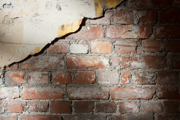 Old red brick wall with crumbling plaster