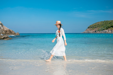 Fototapeta na wymiar A healthy woman in a white dress walks on the beach.