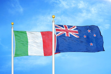Fototapeta premium Italy and New Zealand two flags on flagpoles and blue cloudy sky