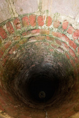 Top view of water well walls made of bricks and covered by moss