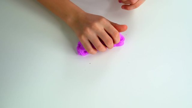 Girls hands play with pink slime on a white table.