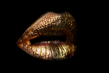 Gold lips. Gold Paint from the lips. Golden lips on beautiful model girls mouth. Make-up. Beauty...