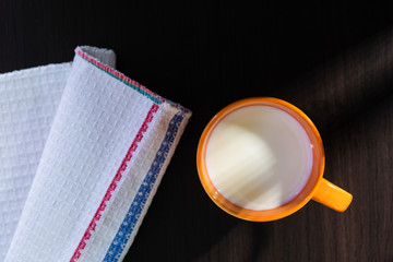 breakfast overhead with cookies and milk in an orange cup and a blue cloth