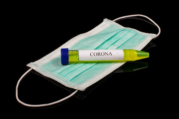 Yellow glowing liquids in the test tube with text CORONA and face mask isolated on the black...