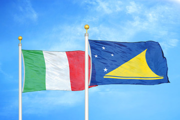 Italy and Tokelau two flags on flagpoles and blue cloudy sky