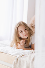 Naklejka premium child girl in a bright interior morning Bali light hair light clothes dreamy smile lifestyle