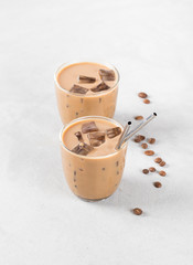 Iced coffee milk in a glass on a light gray background