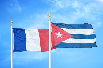 France and Cuba two flags on flagpoles and blue cloudy sky