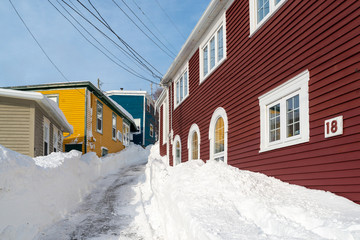 Multiple vintage wooden buildings with colourful exteriors on a hill. The street is covered in...