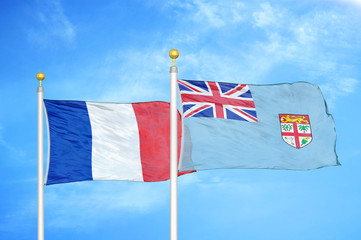 France and Fiji two flags on flagpoles and blue cloudy sky