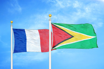 France and Guyana two flags on flagpoles and blue cloudy sky