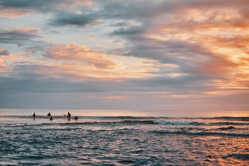 Sunrise with surfers in the ocean 