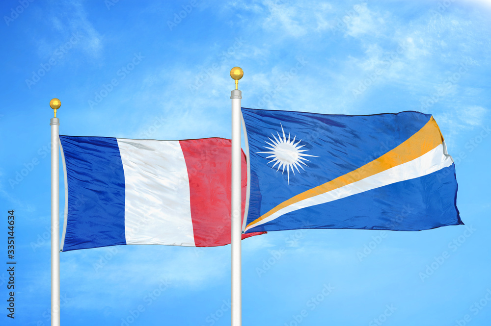 Wall mural france and marshall islands two flags on flagpoles and blue cloudy sky