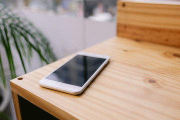 One white smartphone on a wooden desk