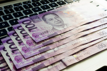 Philippine money on top of a laptop's keyboard