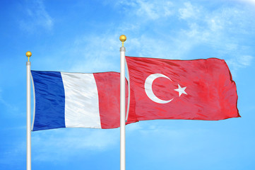 France and Turkey two flags on flagpoles and blue cloudy sky
