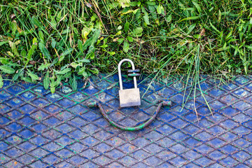 closed metal hatch with padlock on grass soil