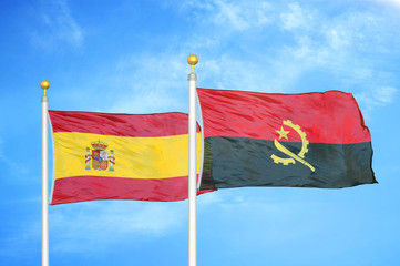 Spain and Angola  two flags on flagpoles and blue cloudy sky