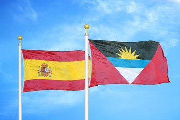 Spain and Antigua and Barbuda  two flags on flagpoles and blue cloudy sky