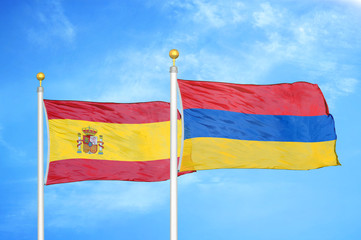 Spain and Armenia  two flags on flagpoles and blue cloudy sky