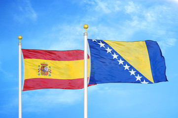 Spain and Bosnia and Herzegovina  two flags on flagpoles and blue cloudy sky