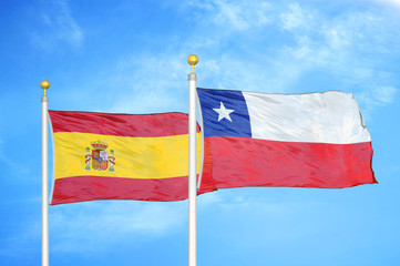 Spain and Chile two flags on flagpoles and blue cloudy sky