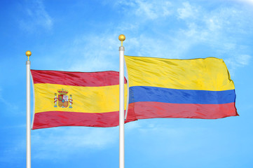 Spain and Colombia two flags on flagpoles and blue cloudy sky
