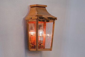 Modern streamlined mirror copper wall lamp. Metal classic lantern on gray background