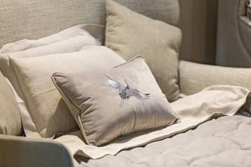 Gray color pillows setting on bed with velor finished style bedding. Pillow with embroidery, soft bed