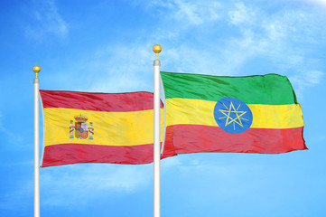 Spain and Ethiopia two flags on flagpoles and blue cloudy sky
