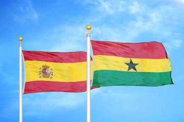 Spain and Ghana two flags on flagpoles and blue cloudy sky