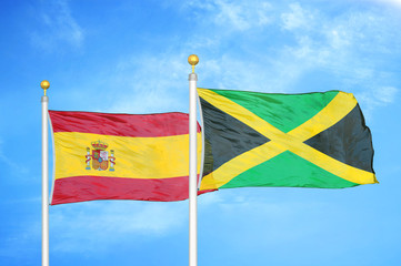 Spain and Jamaica two flags on flagpoles and blue cloudy sky