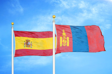 Spain and Mongolia two flags on flagpoles and blue cloudy sky